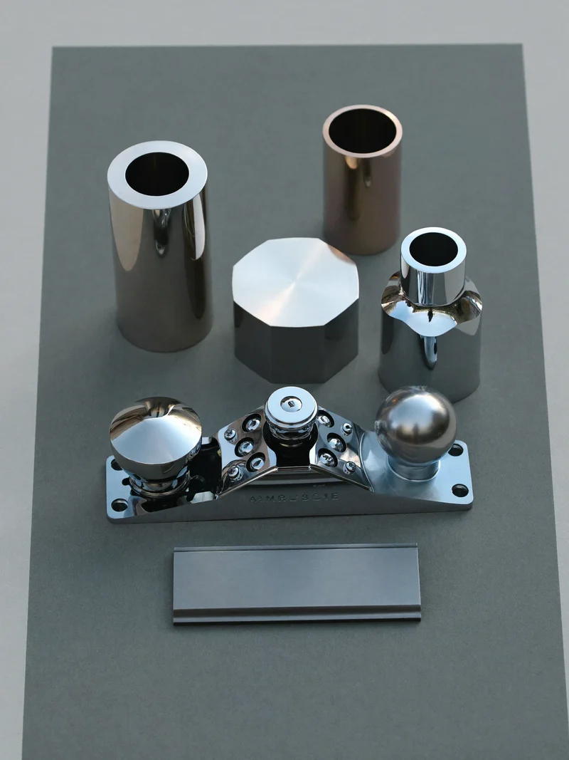Illustration: Gefräste Metallteile und ein Handhobel auf neutral grauem Papierhintergrund